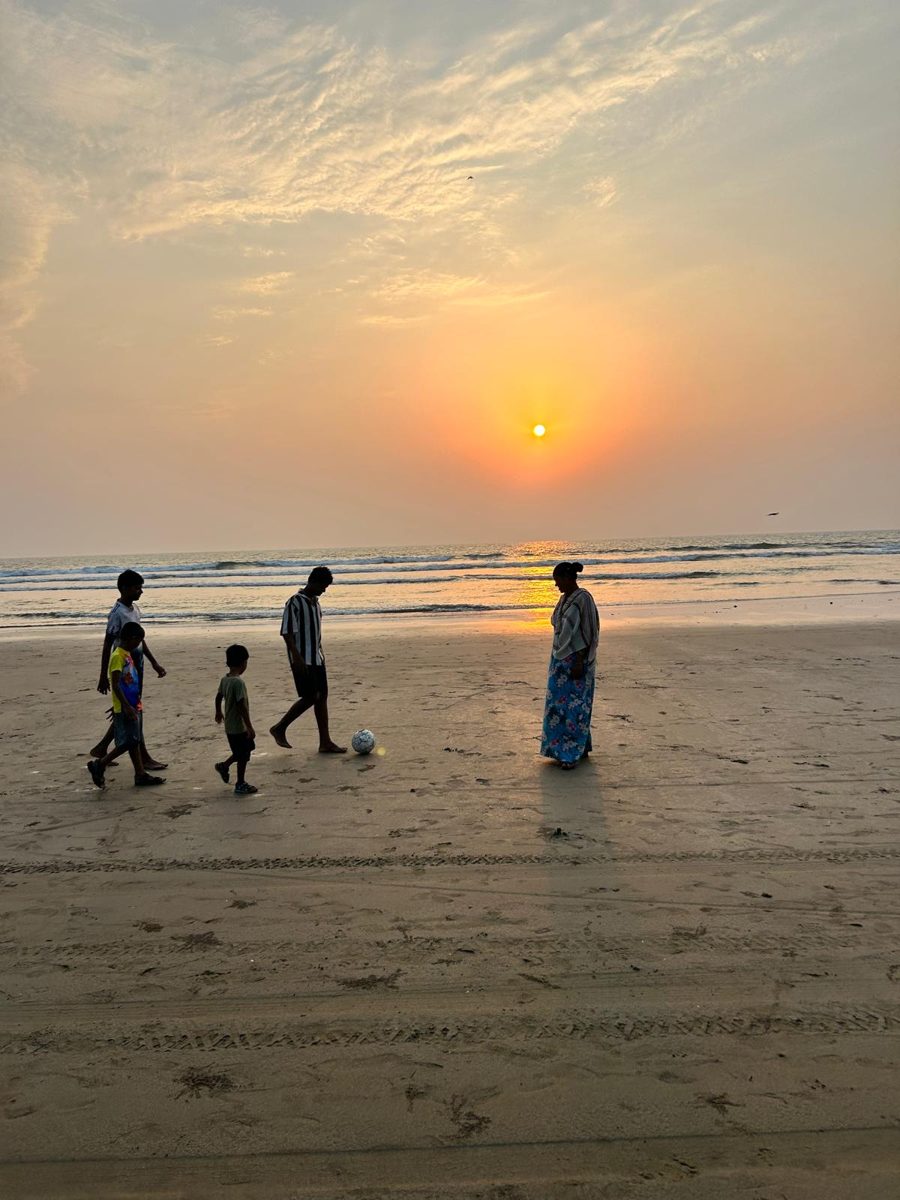 Children and a grown-up playing football on the beach at sunset in Arambol