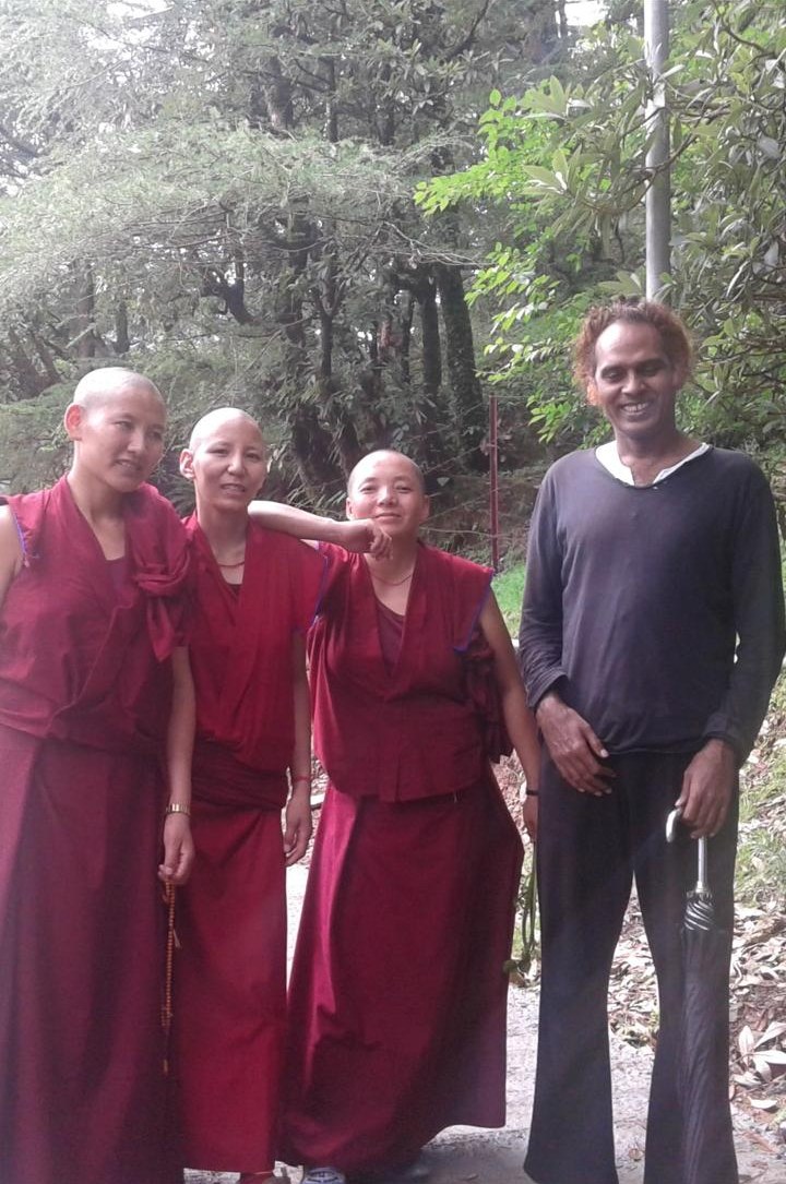 Ramabuddha standing with three monks on a tree-lined path